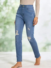High-waisted light-wash blue denim distressed jeans with ripped details on knees and thighs