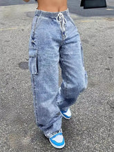 High-waisted drawstring cargo jeans in light-wash denim featuring multiple pockets and a comfortable drawstring waist