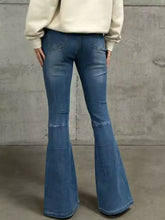 High-waisted blue denim flare jeans with slightly worn distressed look and classic back pockets with tape measure