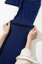 Dark blue high-waisted flare jeans made of denim held open by hands showing a perfect fit and flare design
