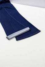 Dark blue high-waisted flare jeans with lighter gray inner lining, clean stitching, and classic tapered leg design