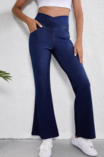 Navy blue high-waisted flare jeans with a cross-over waistband and side pockets in a flared yoga pants style
