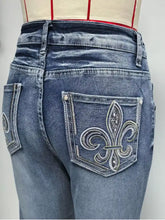 Back side of blue high waisted flare leg denim jeans with silver fleur de lis embroidery recommend measuring for fit
