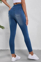 High-waisted skinny blue denim leggings with a fitted stretchy design and classic back pocket seen from the back