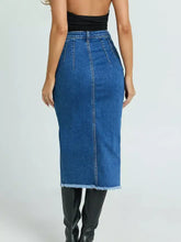 High-waisted mid-thigh length slit denim skirt with frayed hem and visible stitching on blue denim fabric