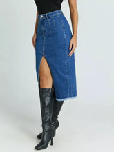 A high-waisted slit denim skirt in classic blue wash with front slit and frayed hem mid-thigh length