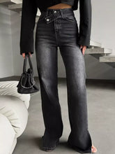 High-waisted black denim slit hem jeans featuring a flared leg and distinctive front button closure