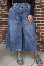 High-waisted wide leg button-fly jeans in medium blue wash denim with subtle fading and a button-front closure