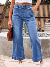 Blue denim high-waisted wide leg flare jeans with a relaxed fit and rolled cuffs for casual wear
