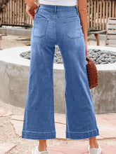 Blue denim high-waisted wide leg flare jeans with classic five-pocket design and rolled cuffs