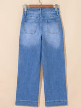 Light-wash blue denim high-waisted wide leg flare jeans with a straight-leg cut hanging on a wooden hanger