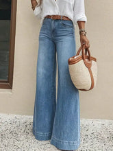 A woven straw tote bag with brown leather handles and trim paired with slightly stretchy high waisted wide leg jeans