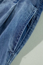 Blue denim high-waisted wide-leg jeans with visible stitching along the seam detail