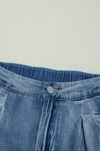 High-waisted wide-leg jeans in blue denim featuring a pleated waistband and silver button closure