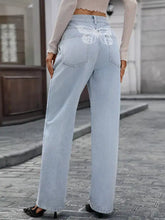 Light blue denim high waisted wide leg jeans with white butterfly embroidery on the back pocket shown from behind