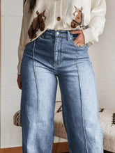 High-waisted light blue denim wide leg jeans with straight-leg cut and visible stitching along the seams