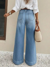 High-waisted light-wash denim wide leg jeans with classic five-pocket design and rolled cuffs
