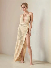 Light-colored crocheted halter neck dress with deep V-neck and high slit