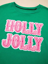 A vibrant green holly jolly embroidered crewneck t-shirt with bold pink and white lettering, slightly stretchy and machine wash
