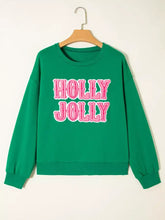 Green holly jolly sweatshirt with pink embroidered lettering, slightly stretchy fabric, machine wash care instructions included
