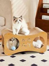 Light wood cat scratcher lounge with toy balls, face cutout, textured surfaces