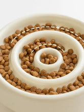 White ceramic interactive slow feeder pet bowl with brown kibble
