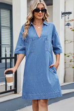 A medium blue wash denim dress with johnny collar, half sleeves, two front pockets, and mid-thigh length design