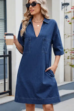 A navy blue denim dress with a johnny collar, two front pockets, and half sleeves in a shirt dress style