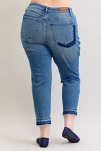 Blue denim judy blue plus size mid rise jeans with frayed hem and brown leather brand patch on waistband back view