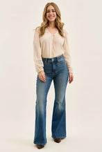 A woman wears judy blue high waist double button tummy control flare jeans in classic blue denim with subtle fading