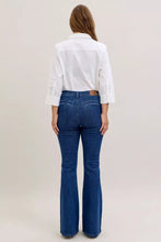 A pair of dark blue high waist flare jeans with classic back pockets and a brown leather brand patch at the waistband