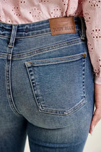 Blue denim judy blue mid rise flare jeans with brown leather brand patch and front flap pockets on waistband