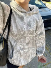 A soft oversized kangaroo pocket long sleeve hoodie in muted silver gray camouflage with relaxed fit and care instructions to machine wash cold