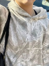 Kangaroo pocket long sleeve hoodie in gray and white camouflage with soft sheer fabric and relaxed fit machine wash cold care instructions