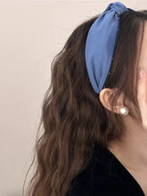 Woman in wavy brown hair wearing knotted polyester wide headband with blue polka dots