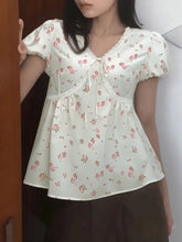 Ivory short sleeve blouse with lace trim and subtle pink floral pattern at neckline and waistband