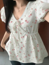 Delicate off-white lace detail short sleeve blouse with soft pink rose print, puffed sleeves, and gathered waist