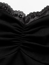 Black lace halter neck cami featuring a lace-trimmed top with a ruched bodice for elegant layering