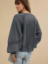 A dark gray oversized mineral wash sweatshirt with intricate black lace trim on sleeves and hem machine wash tumble dry low