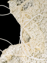 Cream-colored lace ruffle trim tie-front cami with delicate textured patterns and white drawstrings in lace fabric