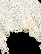 A delicate off-white lace ruffle trim shawl with a floral pattern and scalloped edges complementing the tie-front cami