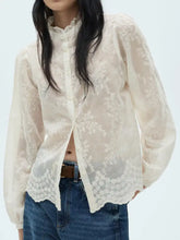 A delicate ivory lace sheer long sleeve blouse with floral embroidery and a high ruffled collar