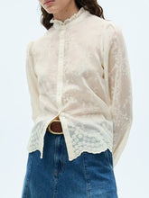 A delicate ivory lace sheer long sleeve shirt with ruffled collar and scalloped hem for elegant wear
