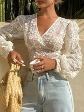 A delicate white lace sheer long sleeve crop top with intricate floral embroidery and puffy long sleeve wrap design