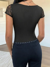 Black lace sweetheart cap sleeve bodysuit with lace trim, fitted silhouette, and silver stud detailing on waistband