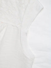 White lace trim notched blouse features lace trim with delicate cap sleeves and a soft textured pattern
