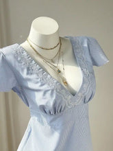 A light blue and white vertically striped blouse with delicate lace trim along the v-neckline