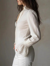 A white semi-sheer blouse with lace trim zip detailing along the front and cuffs in a lace trim zip-up shirt