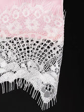 A lace trimmed satin cami featuring a delicate white lace shawl with floral patterns layered over soft pink fabric
