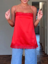 A vibrant red lace trimmed satin camisole with delicate lace trim along the neckline and hem